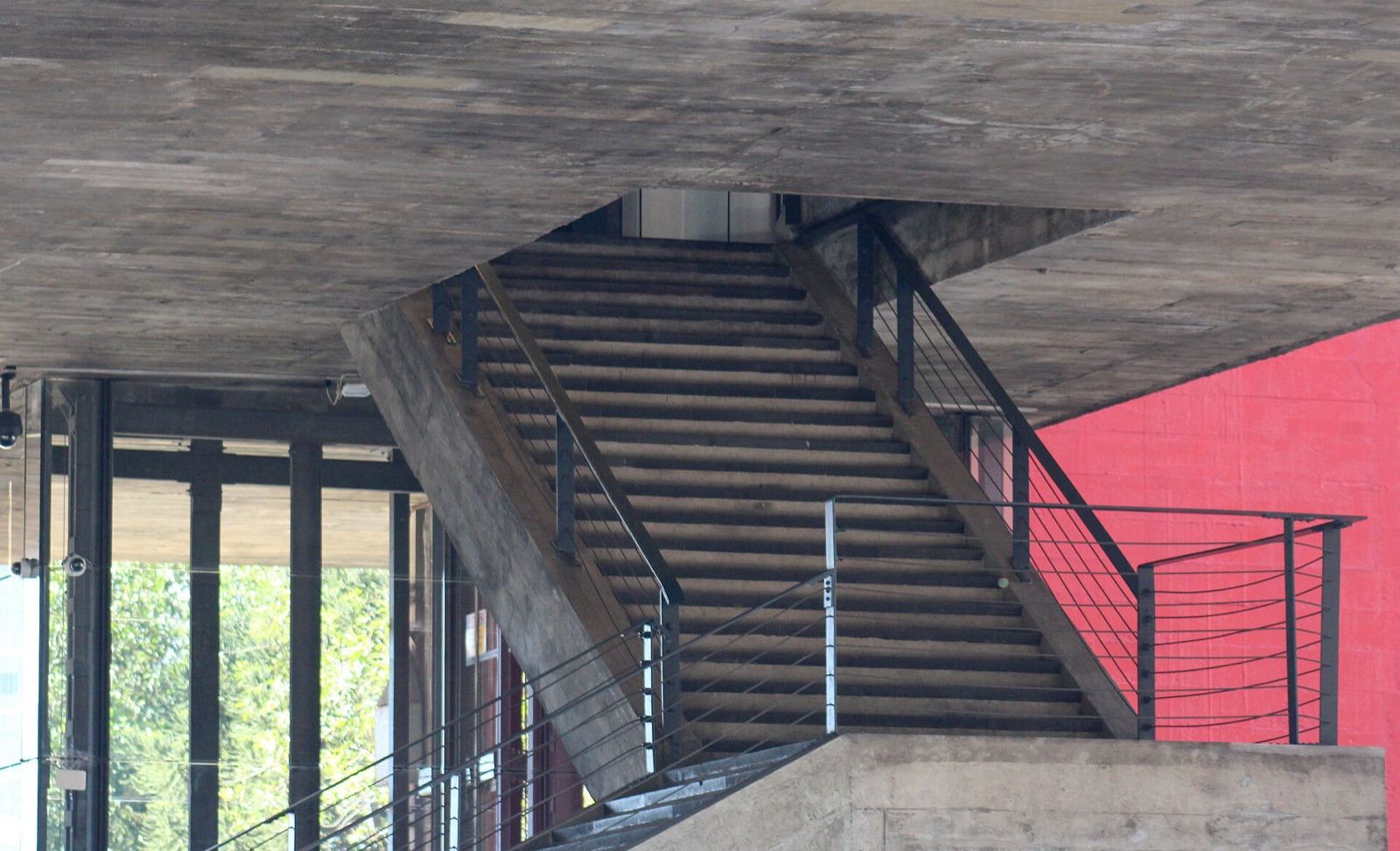 A escada que desce do vão livre: concreto aparente e a estrutura sempre à mostra